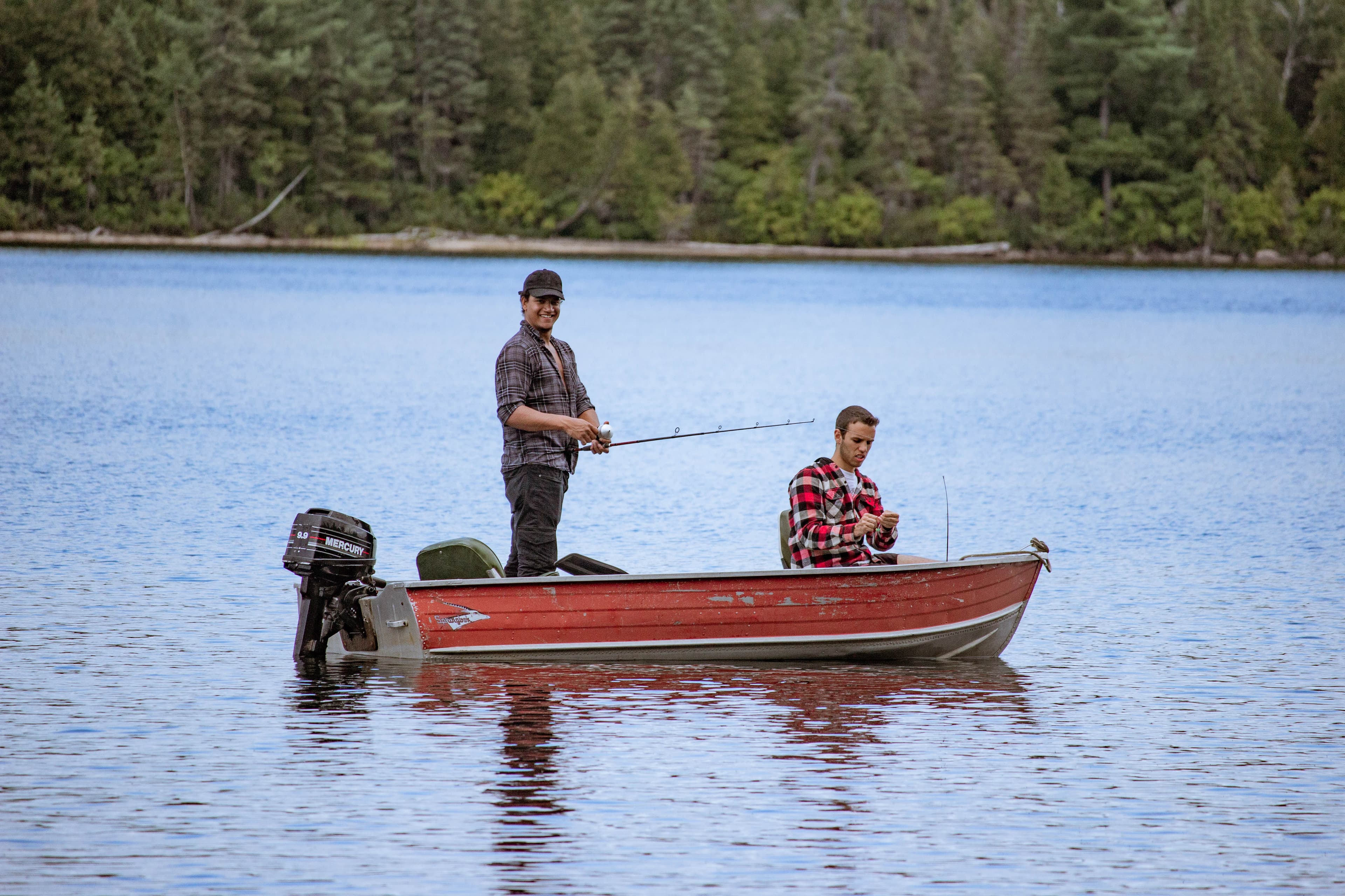 A close up photograph of two men in a boat on a lake