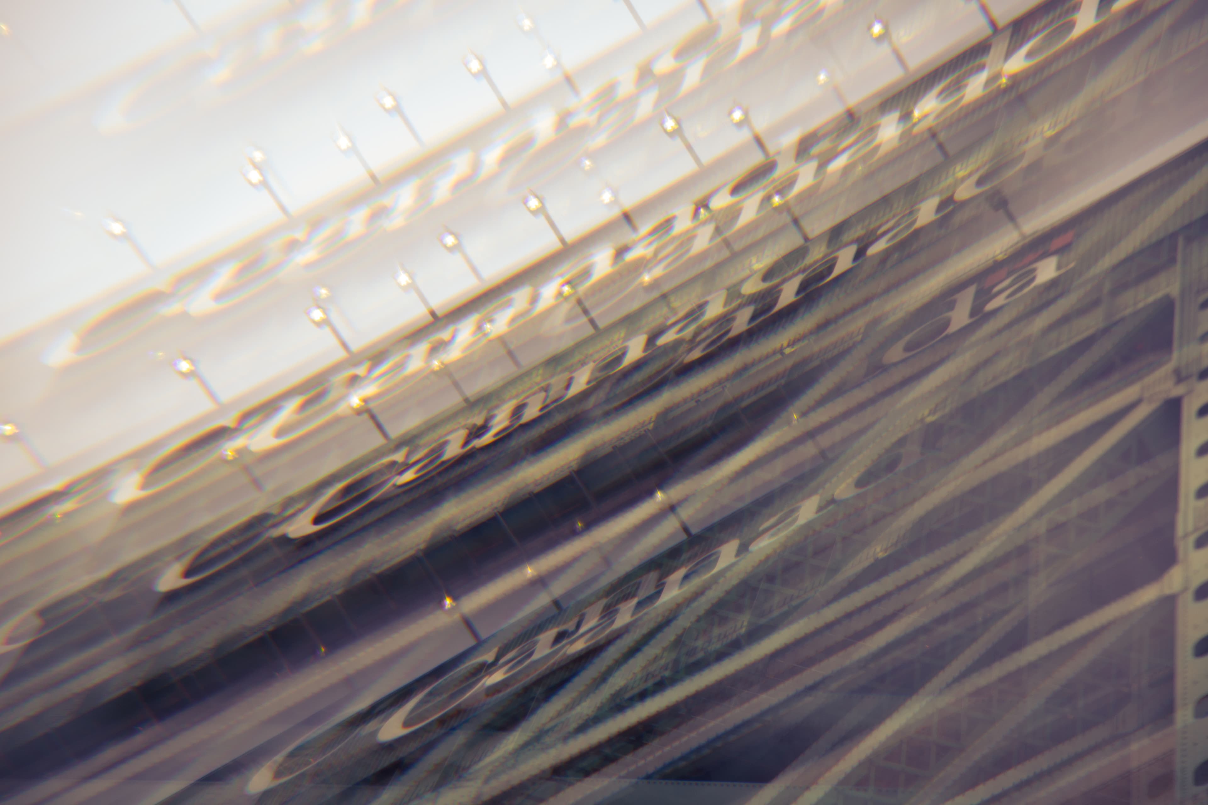 A photograph of a metal sign reading ‘Canada’ taken through a glass prism with an array of refractions scattered across the image